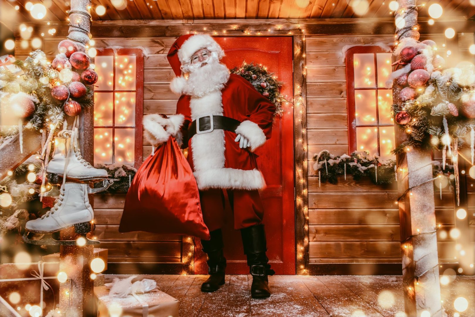 Santa standing outside festive decorated house with a sack of presents